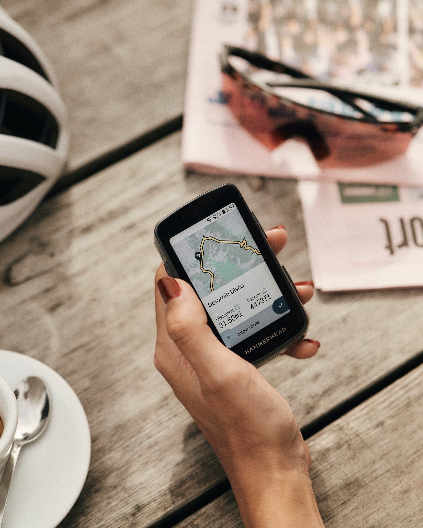 Hand holding a smartphone with a map app on a wooden table