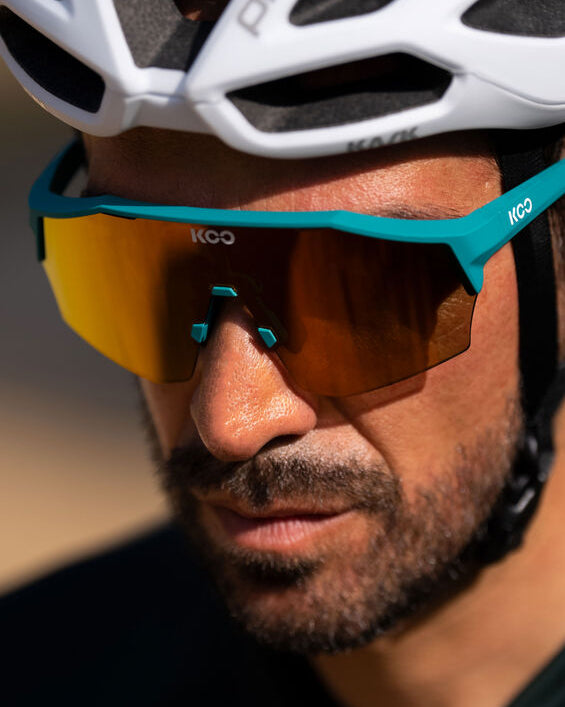 Person wearing a white bicycle helmet and blue sunglasses with a blurred background