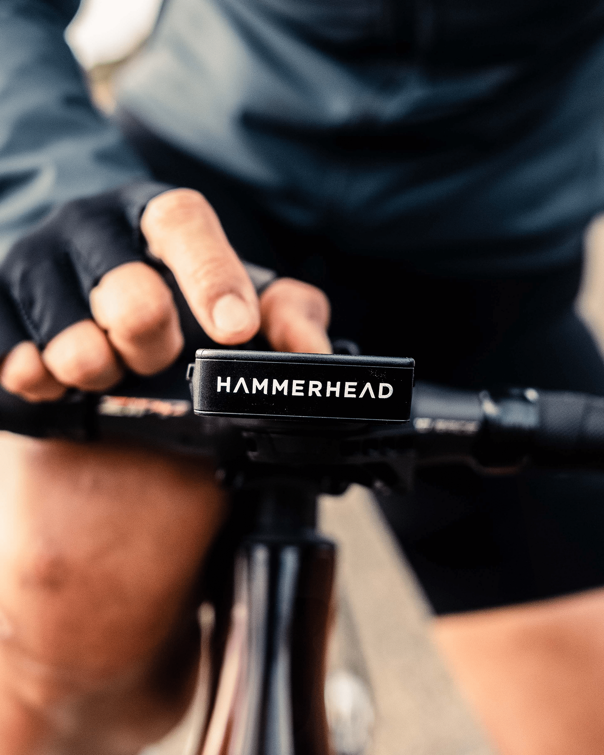 Close-up of a person holding bicycle handlebars with 'HAMMERHEAD' branding.