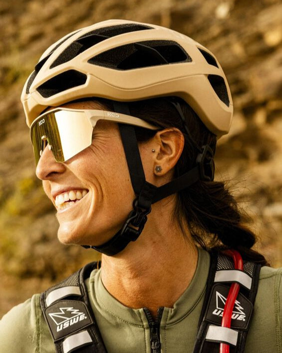 Person wearing a helmet and sunglasses with a blurred natural background