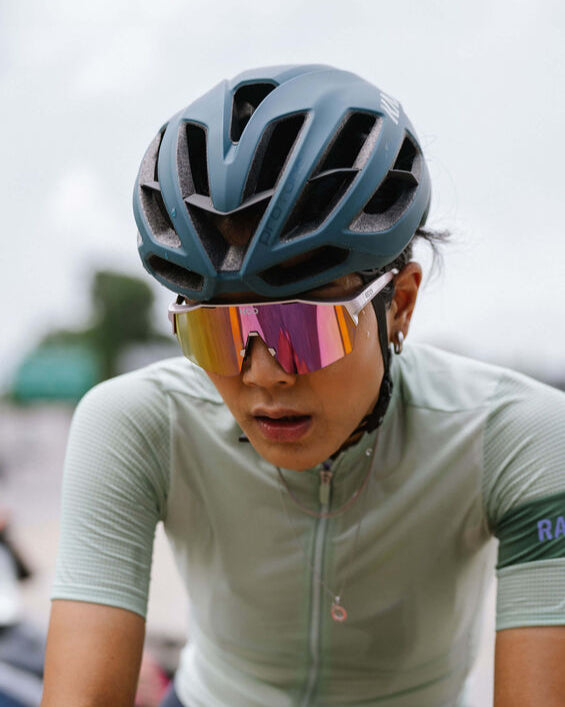 Person wearing a helmet and cycling outfit with colorful sunglasses.